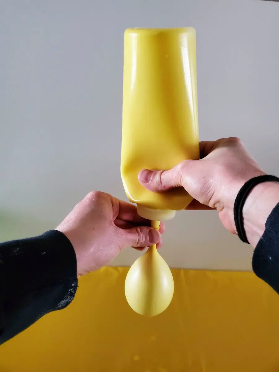 Filling a Balloon with Yellow Paint Using a Reusable Condiment Bottle